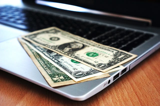 three one dollar bills sitting on the edge of a laptop
