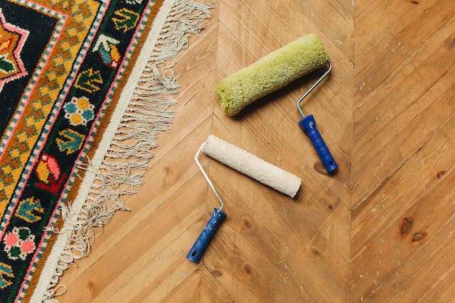 Two paint rollers on a wood floor