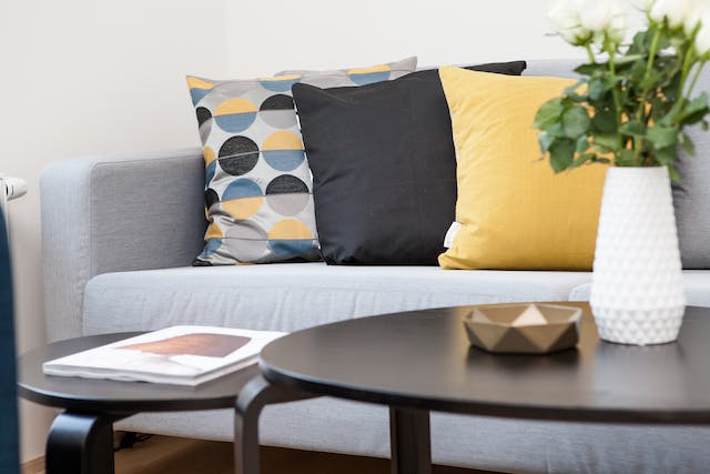 Grey sofa with three pillows on it